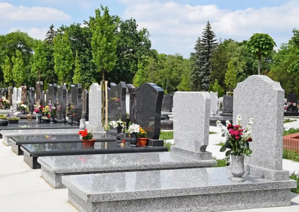 Allée de cimetière avec des monuments funéraires et pierres tombales en granit gris et noir fleuries